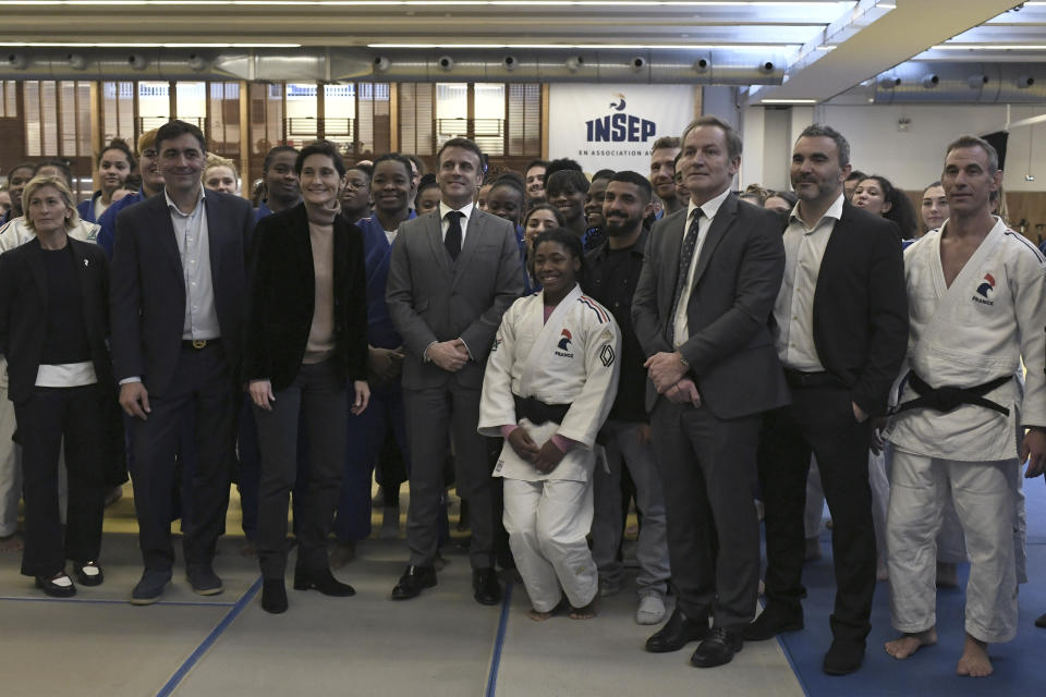 French President Emmanuel Macron, centre, and French Minister of Education, Sports, and Olympic Games Amelie Oudea-Castera, centre left, pose with athletes during their visit to France's National Institute of Sport, Expertise, and Performance (INSEP), prior to the president presenting his New Year's wishes to elite athletes ahead of the Paris 2024 Olympic and Paralympic Games, in Paris, Tuesday, Jan. 23, 2024. (Stephane De Sakutin/Pool Photo via AP)