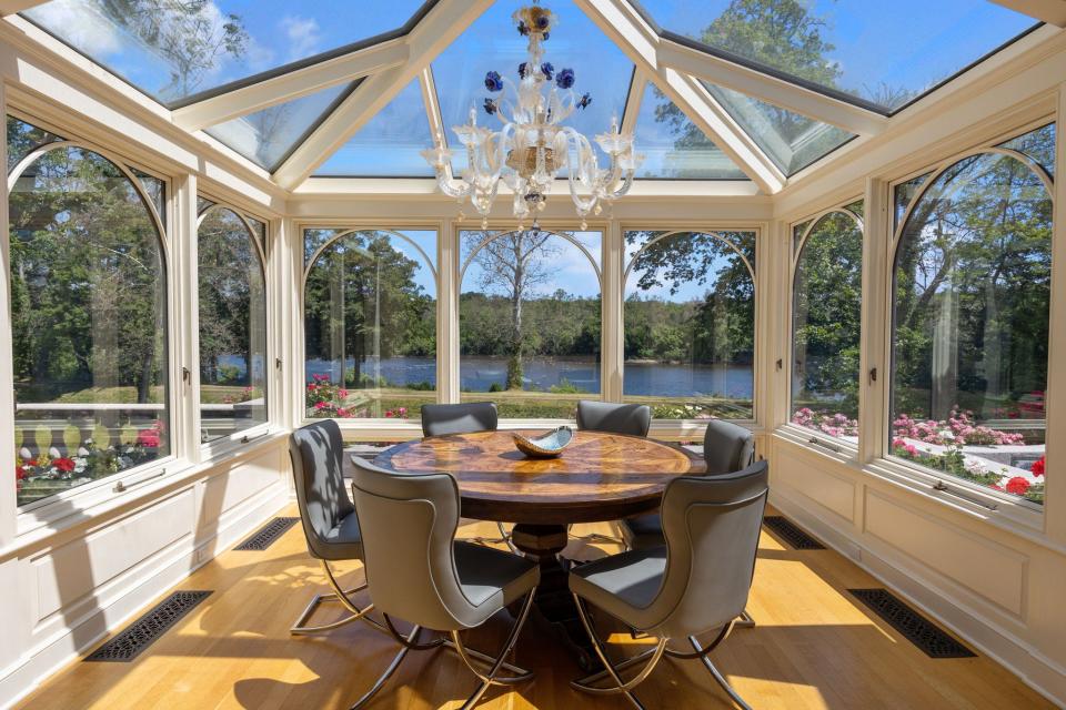 A glass conservatory located off the kitchen provides a space to enjoy a meal while taking in picturesque waterfront views.