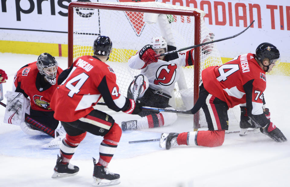 New Jersey Devils center Nico Hischier (13) crashes into the Ottawa Senators net as Senators goaltender Craig Anderson, Jean-Gabriel Pageau and Mark Borowiecki defend during third-period NHL hockey game action in Ottawa, Ontario, Sunday, Dec. 29, 2019. (Sean Kilpatrick/The Canadian Press via AP)