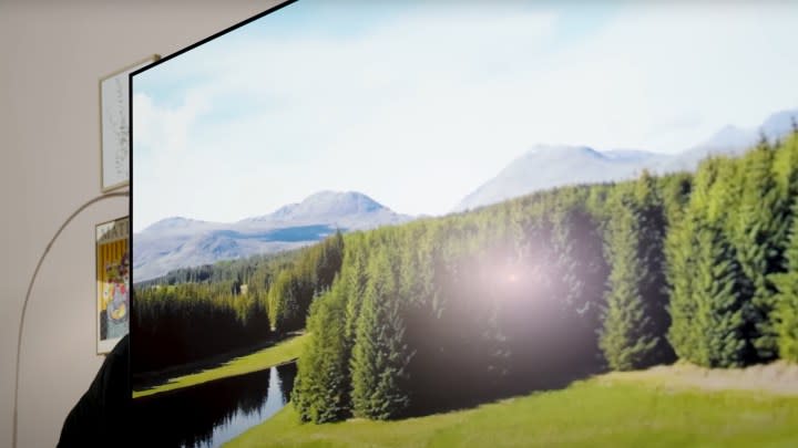 A glare from lights is seen on Samsung S95D OLED TV displaying a natural vista. 