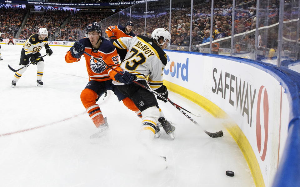 Boston Bruins defenseman Charlie McAvoy (73) and Edmonton Oilers' Ryan Nugent-Hopkins (93) battle for the puck during the second period of an NHL hockey game, Wednesday, Feb. 19, 2020 in Edmonton, Alberta. (Jason Franson/The Canadian Press via AP)