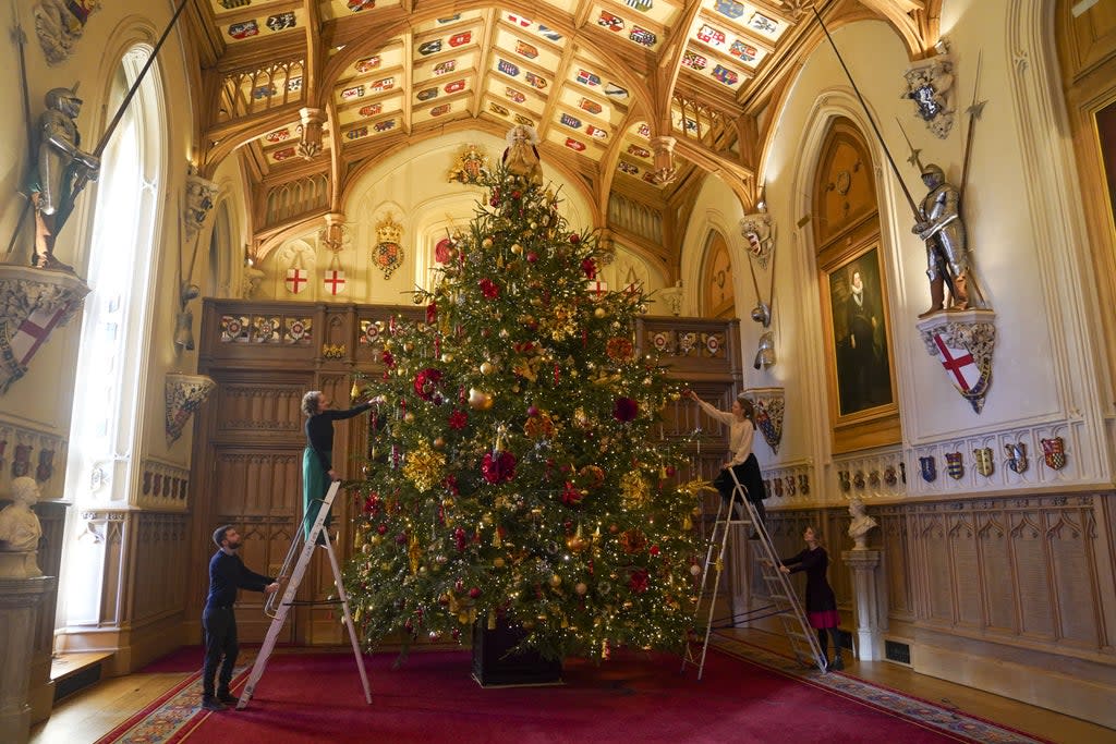 Members of the Royal Collection Trust staff put the finishing touches to a Christmas tree in St George’s Hall (Steve Parsons/PA) (PA Wire)