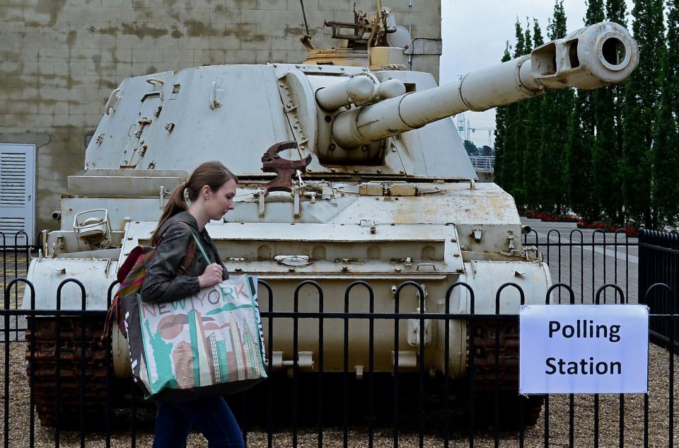 A woman walks past an 2S3 M-1973 Akatsiya 152-mm self-propelled gun howitzer, standing outside the Greenwich Heritage Centre, set up as a polling station, in London on June 23, 2016.