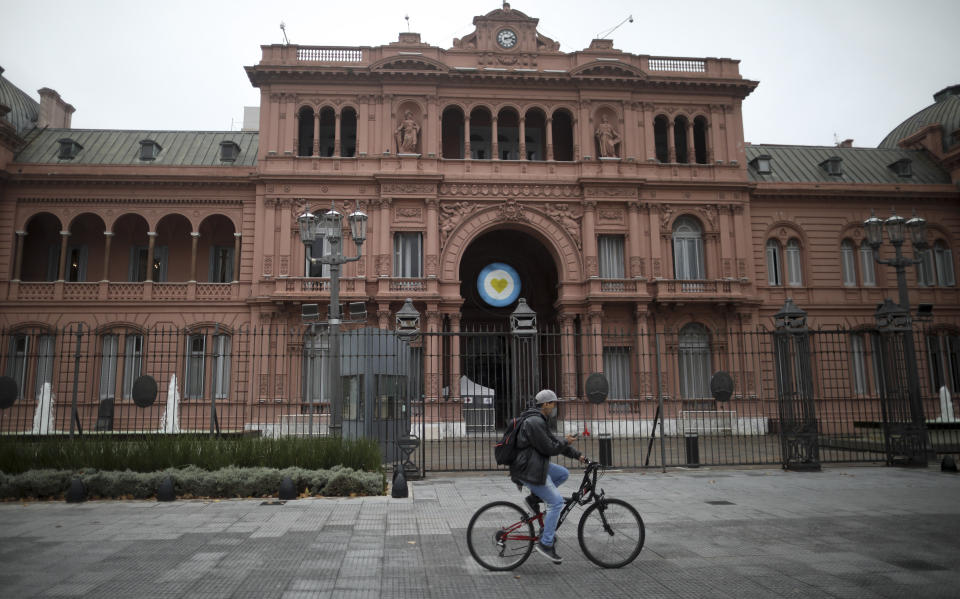 ARCHIVO - En esta imagen de archivo del 21 de mayo de 2020, un hombre pasa en bicicleta ante la sede de gobierno durante una cuarentena contra el COVID-19 en Buenos Aires, Argentina. Desde Argentina a Panamá, varios funcionarios públicos se han visto obligados a renunciar ante crecientes reportes sobre la compra fraudulenta de respiradores, mascarillas y otros suministros médicos. (AP Foto/Natacha Pisarenko, Archivo)