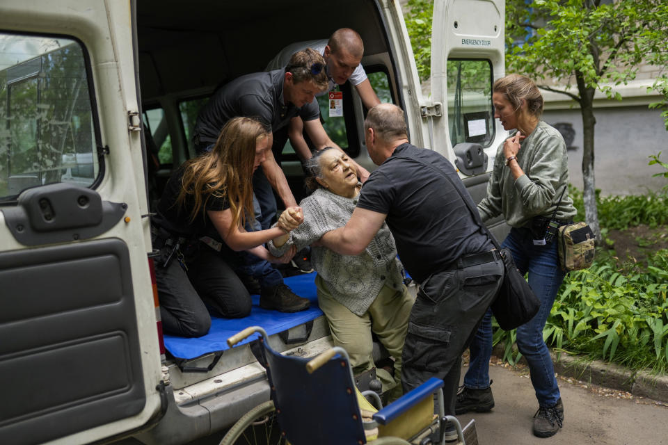 A woman is carried from her home in an evacuation by British volunteers group BEAR in Bakhmut, eastern Ukraine, Friday, May 27, 2022. Volunteers have been racing to evacuate as many civilians as possible, particularly the elderly and those with mobility issues, as Russian forces make advances in the region. (AP Photo/Francisco Seco)