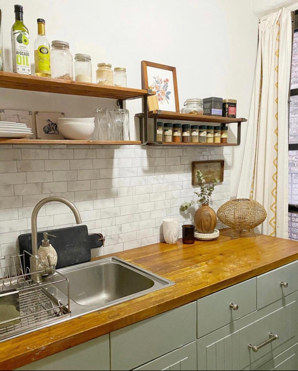 A kitchen with butcher-block countertops, open shelving, and a white backsplash.