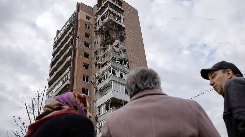 Local residents stand in a front of an apartment building hit by a Russian drone strike in Kharkiv, Ukraine, on April 4, 2024. - Yevhen Titov/Reuters