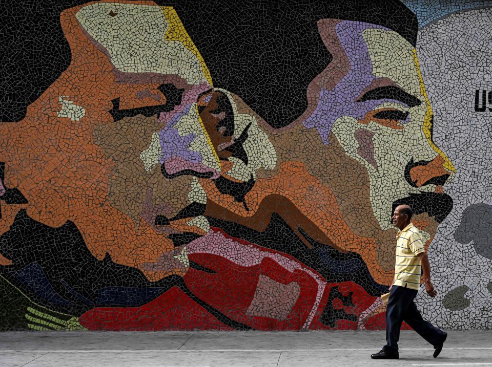 A man walks past a mosaic depicting late Venezuelan President Hugo Chavez (left) and Venezuelan president Nicolas Maduro in Caracas, Venezuela, on January 30, 2019.