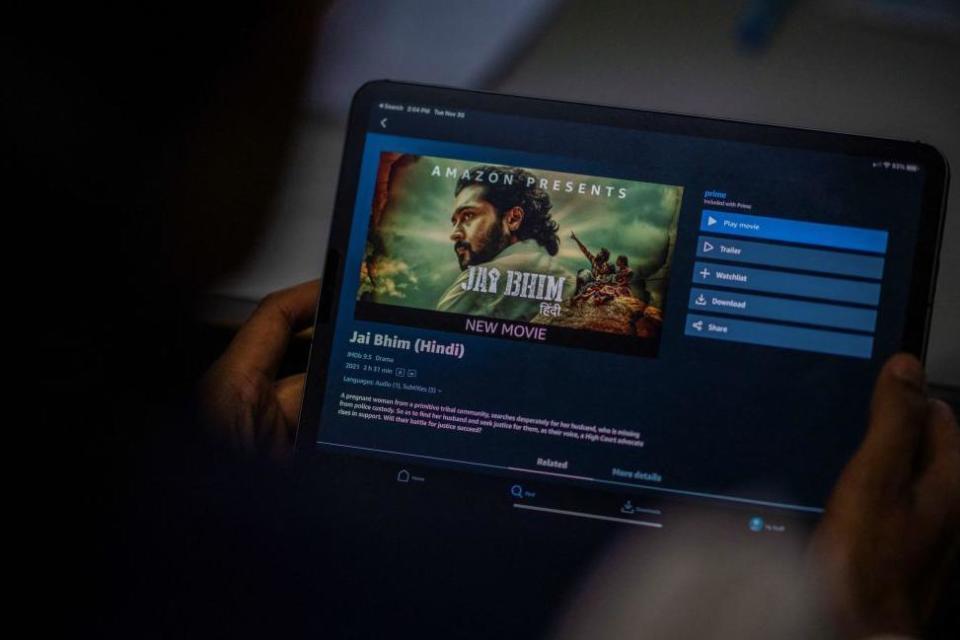 In this photo illustration taken on November 30, 2021, a man prepares to watch the Hindi dubbed Tamil legal drama 'Jai Bhim' on the Amazon Prime Video app in New Delhi. -