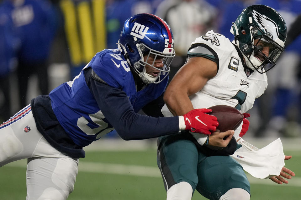 New York Giants linebacker Bobby Okereke (58) tries to strip the ball from Philadelphia Eagles quarterback Jalen Hurts (1) during the second quarter of an NFL football game, Sunday, Jan. 7, 2024, in East Rutherford, N.J. (AP Photo/Seth Wenig)