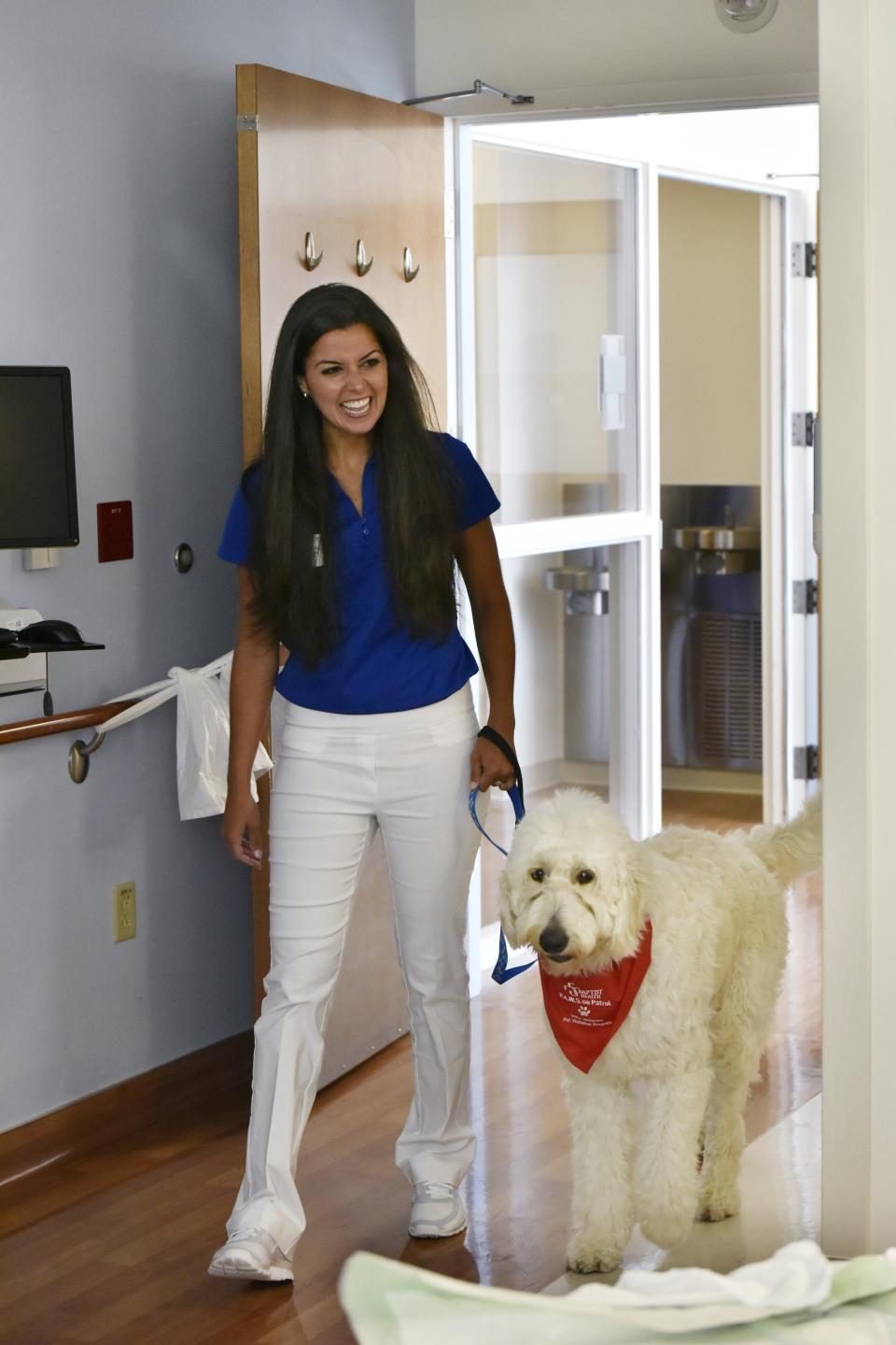 In this 2016 photo, Melissa Loeffelholz brings her dog Oscar, an English Goldendoodle, into a patient's room at Baptist Medical Center. Oscar was part of the hospital's Grace Anderson Pet Visitation Program designed to provide comfort to patients during their stay. Loeffelholz began participating as a way to give back she said, following a car crash that left her hospitalized for long periods.