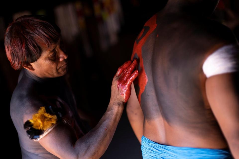 A Yawalapiti man paints his son (Reuters)