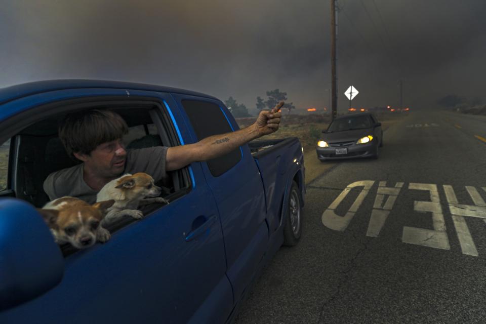 A resident flees as the Bobcat fire approaches Cima Mesa Road in Juniper Hills.