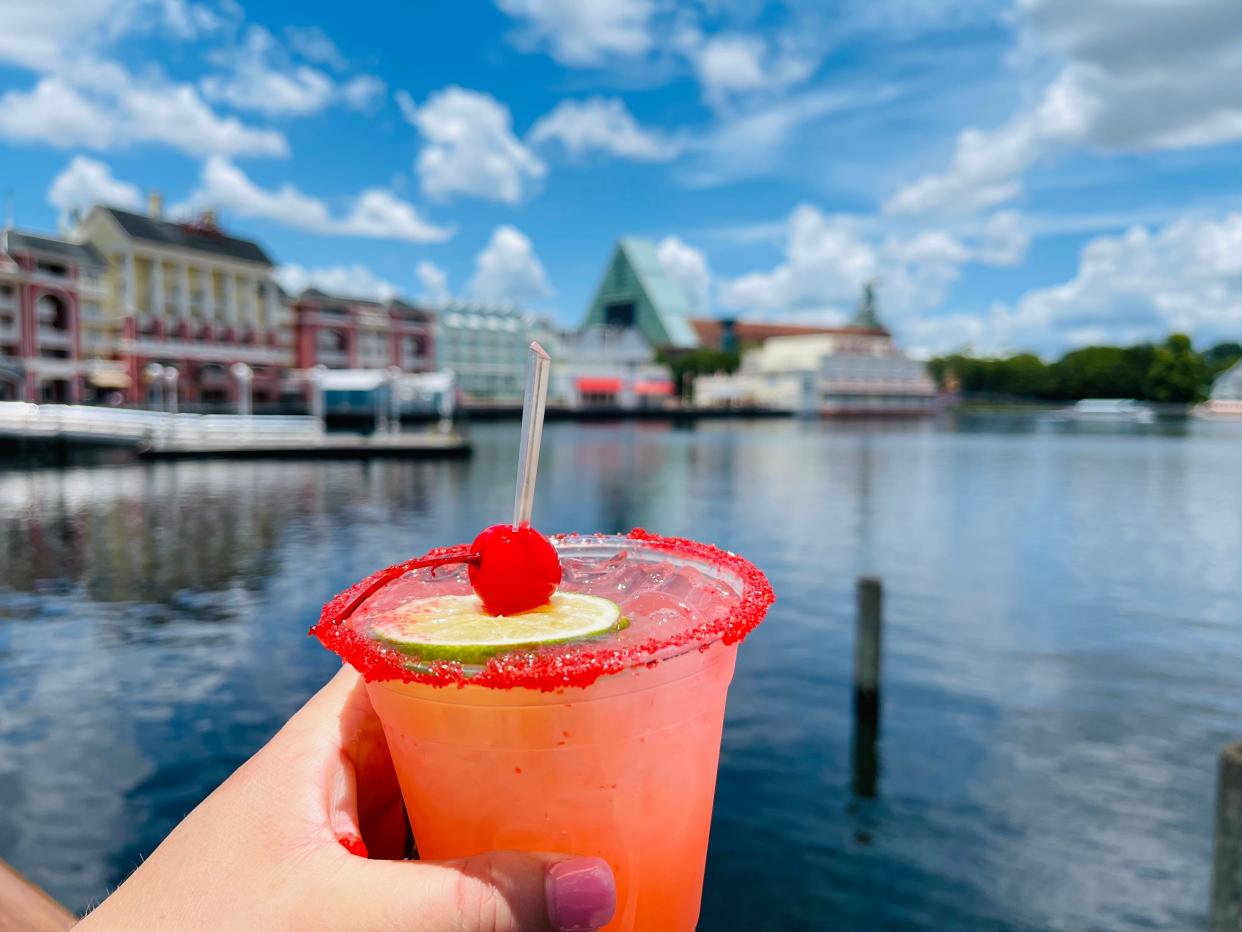 hand holding drink on the boardwalk at disney world