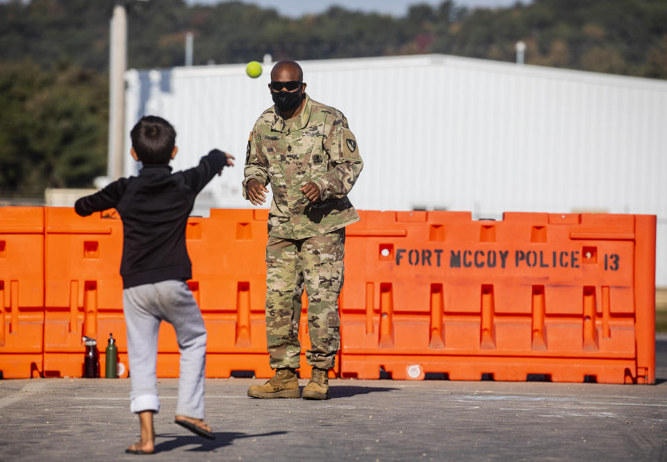 First Sgt. Abraham plays catch with an Afghan refugee child in the Village where Afghans are living temporarily at the Ft. McCoy U.S. Army base on Thursday, Sept. 30, 2021 in Ft. McCoy, Wis. The fort is one of eight military installations across the country that are temporarily housing the tens of thousands of Afghans who were forced to flee their homeland in August after the U.S. withdrew its forces from Afghanistan and the Taliban took control. (Barbara Davidson/Pool Photo via AP)