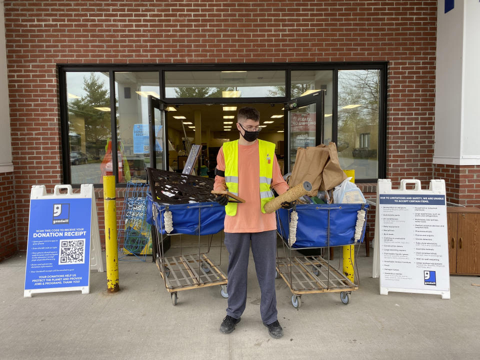 In this undated photo provided by Goodwill Northern New England, a donation attendant working for Goodwill Northern New England at the Westbrook, Maine, store looks at a broken picture frame and a broken cat scratching post. Experts note the coronavirus pandemic has encouraged many to clean their homes and get rid of stuff they don’t want. And during the past year, several Goodwill agencies say they've seen an increase in unwanted donations, and in turn, their trash bills. (Heather Steeves/Goodwill Northern New England via AP)