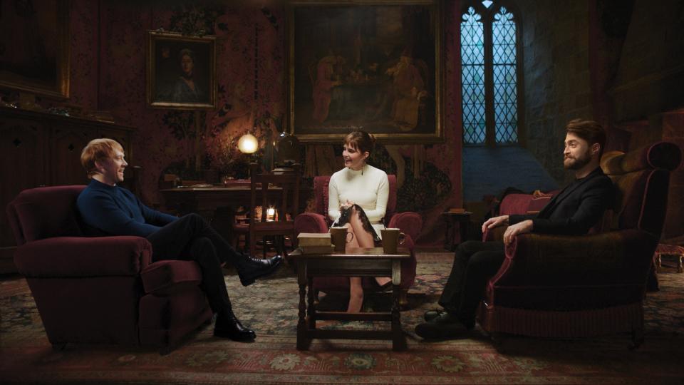 rupert grint, emma, watson, and daniel radcliffe sitting together in the gryffindor common room set during the harry potter 20th anniversary special