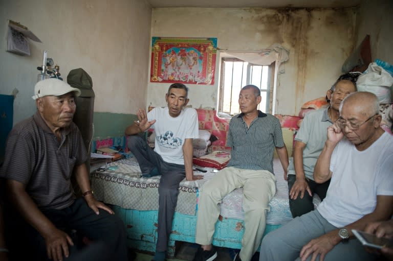 Farmer Wang Enlin (2nd L) sits in his house with fellow environmental activists who have taken on a subsidiary of China's largest chemical firm, accusing it of polluting and destroying farmland