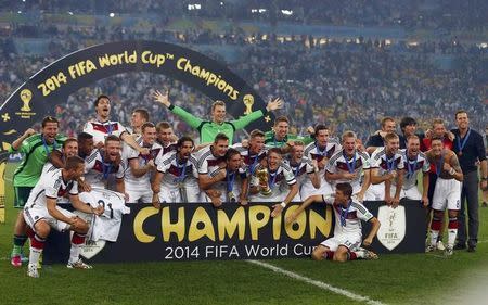 Germany's players pose for pictures as they celebrate with their World Cup trophy after winning their 2014 World Cup final against Argentina at the Maracana stadium in Rio de Janeiro July 13, 2014. REUTERS/Michael Dalder