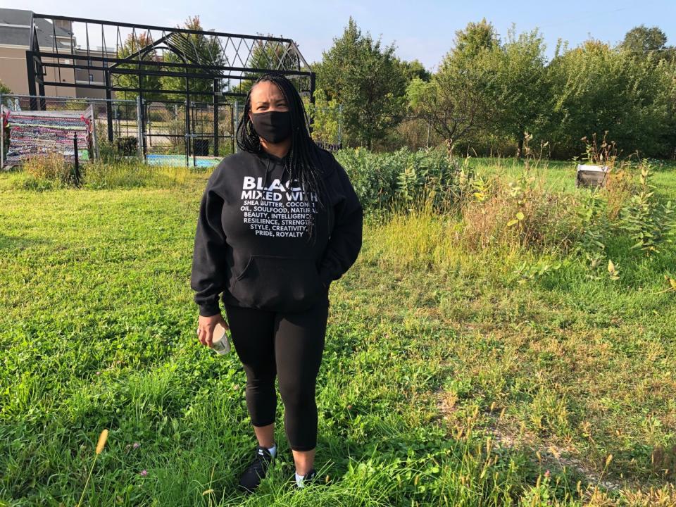 A woman stands in a community garden.