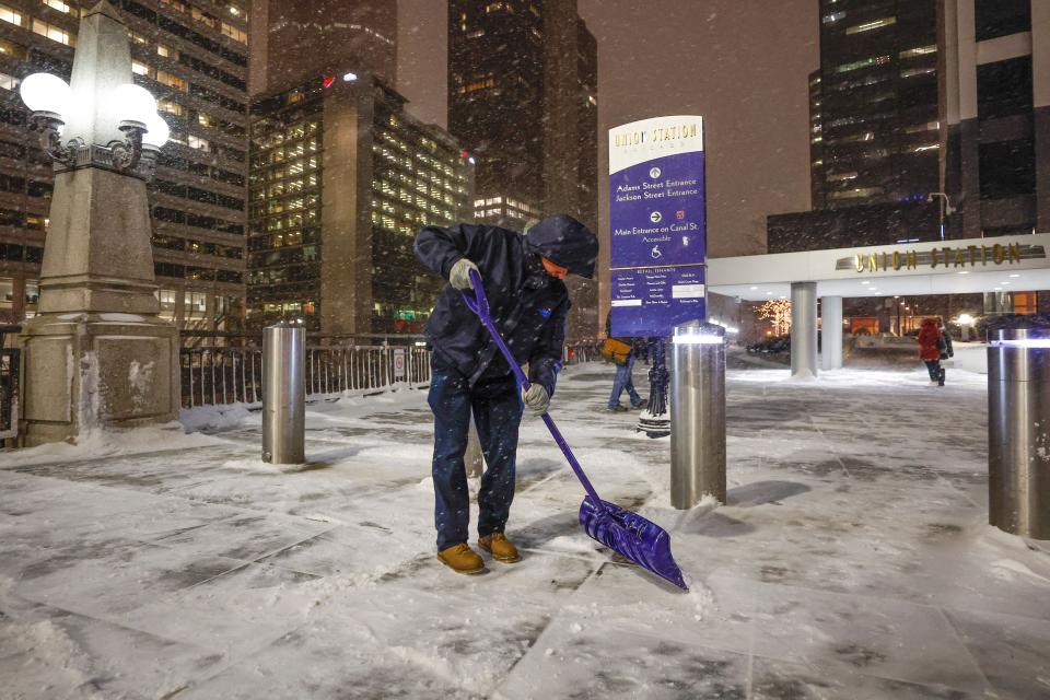 man clears a sidewalk during a winter storm ahead of the Christmas Holiday outside the Union Station in Chicago on December 22, 2022.