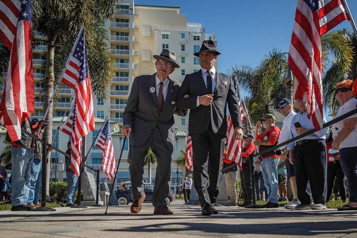 Delmas P. Wood, Jr., impersonating former President Franklin D. Roosevelt, left, of Boynton Beach, enters Veterans Memorial Park with Chris Salamone, impersonating a Secret Service officer, right, of Delray Beach during the Pearl Harbor remembrance and monument dedication in Boynton Beach, Fla., on Tuesday, December 7, 2021. This year marks the 80th anniversary of the Japanese attack.