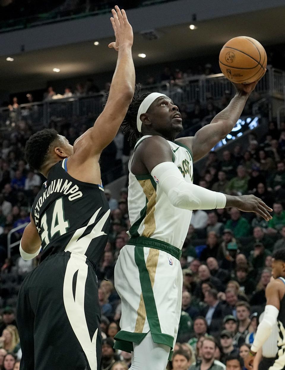 Boston Celtics guard Jrue Holiday (4) shoots over Milwaukee Bucks forward Giannis Antetokounmpo (34) during the first half of their game Thursday, January 11, 2024 at Fiserv Forum in Milwaukee, Wisconsin.