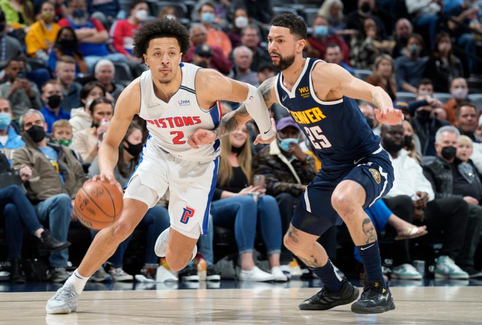 Detroit Pistons guard Cade Cunningham, left, drives past Denver Nuggets guard Austin Rivers in the first half of an NBA basketball game Sunday, Jan. 23, 2022, in Denver.