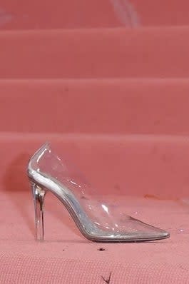 Zendaya's clear high-heeled shoe on pink surface, reminiscent of Cinderella's glass slipper