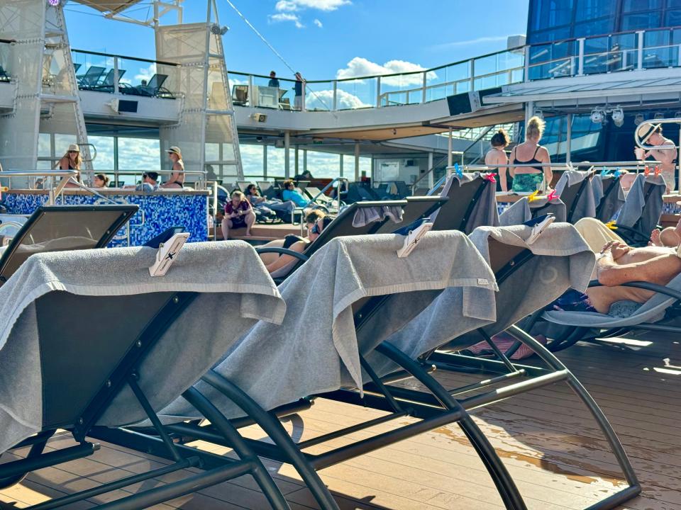 towels clipped to the back of pool chairs on a pool deck of a cruise