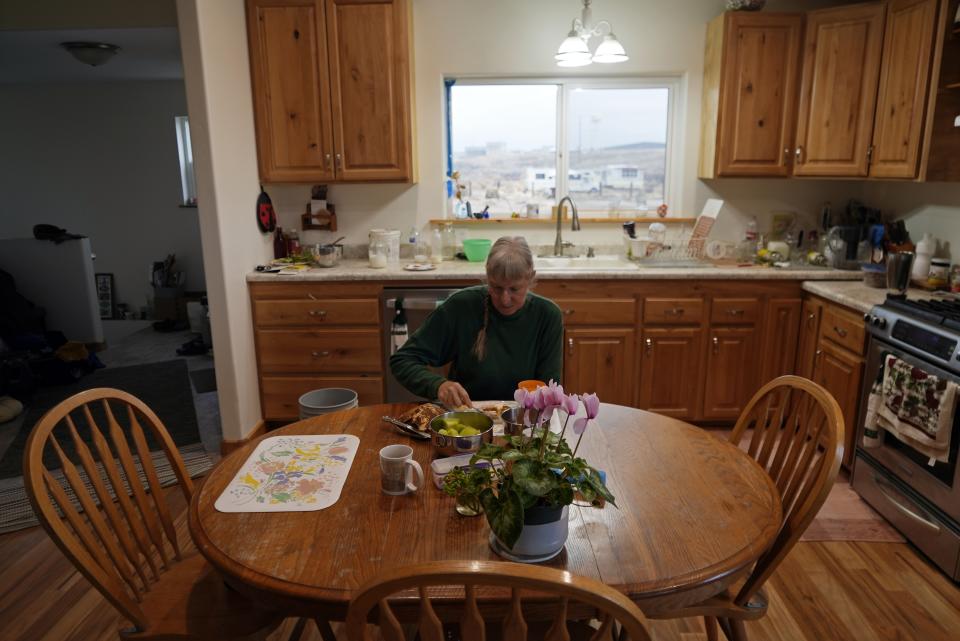 Gayna Salinas eats breakfast in her kitchen Thursday, Jan. 25, 2024, in Green River, Utah, with a view of an abandoned uranium mine behind her. An Australian company and its U.S. subsidiaries are eyeing a nearby area to extract lithium, metal used in electric vehicle batteries. Salinas, whose family farms in the rural community, said she was skeptical about the project's benefits. (AP Photo/Brittany Peterson)