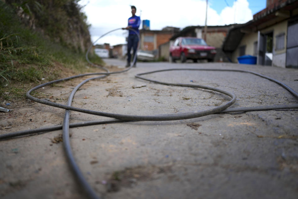 Franklin Caceres carries a hose to fill up a neighbor's water tank, pumped from a well in the Petare neighborhood of Caracas, Venezuela, Monday, March 20, 2023. Caceres supplies water to more than 400 people in the upper sector of Petare as the celebration of World Water Day on March 22 is set to coincide with the start of the UN 2023 Water Conference in New York, aimed at solving the water and sanitation crisis. (AP Photo/Matias Delacroix)