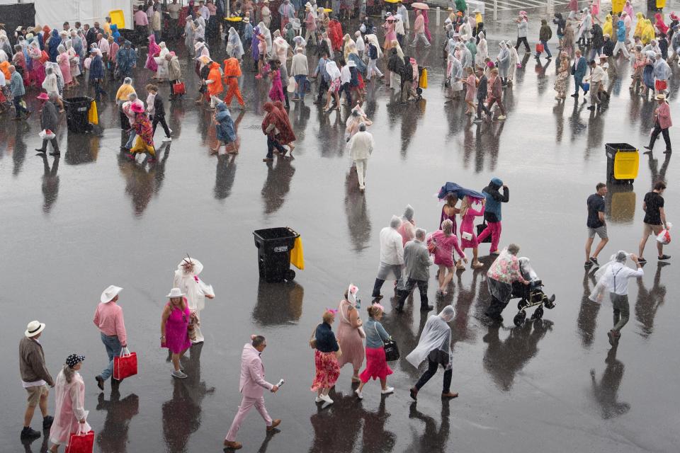 People exit Churchill Downs after the 150th running of the Kentucky Oaks as the rain comes down on Friday, May 3, 2024.