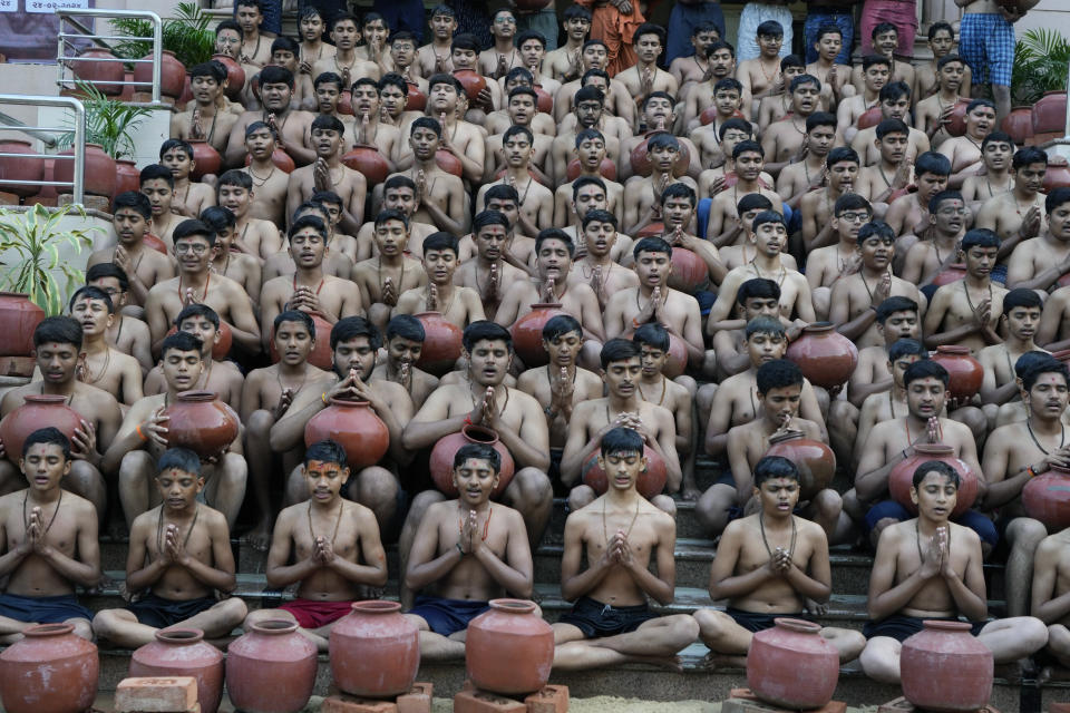 Indian students of the Swaminarayan Gurukul pray after demonstrating a ritualistic bath called Magh Snan for the media in Ahmedabad, India, Wednesday, Jan. 24, 2024. Devotees believe that a purification bath taken during the auspicious Hindu calendar month of Magh, which begins Thursday, will absolve them of their sins. (AP Photo/Ajit Solanki)