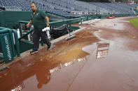 A Washington Nationals crew member walks past water before the beginning of a Philadelphia Phillies at Washington Nationals baseball game, Sunday, Oct. 2, 2022, in Washington. (AP Photo/Luis M. Alvarez)