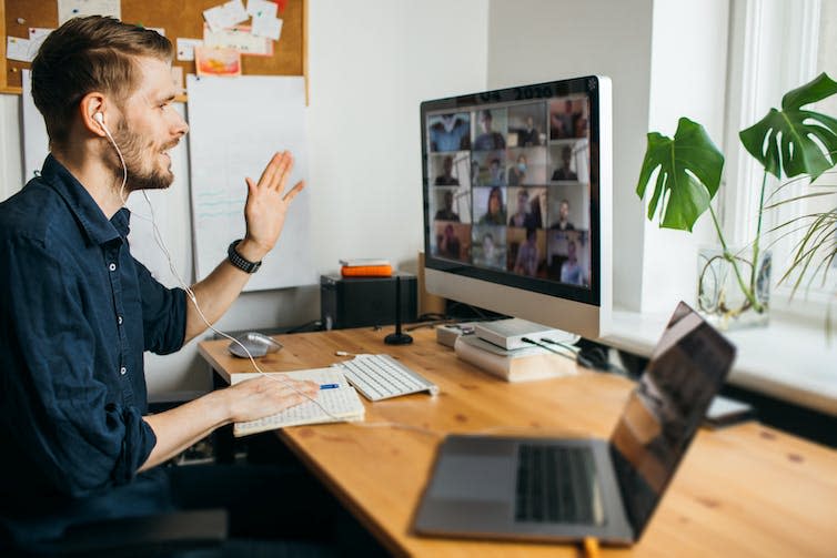 A man on a video call on his computer with multiple participants.