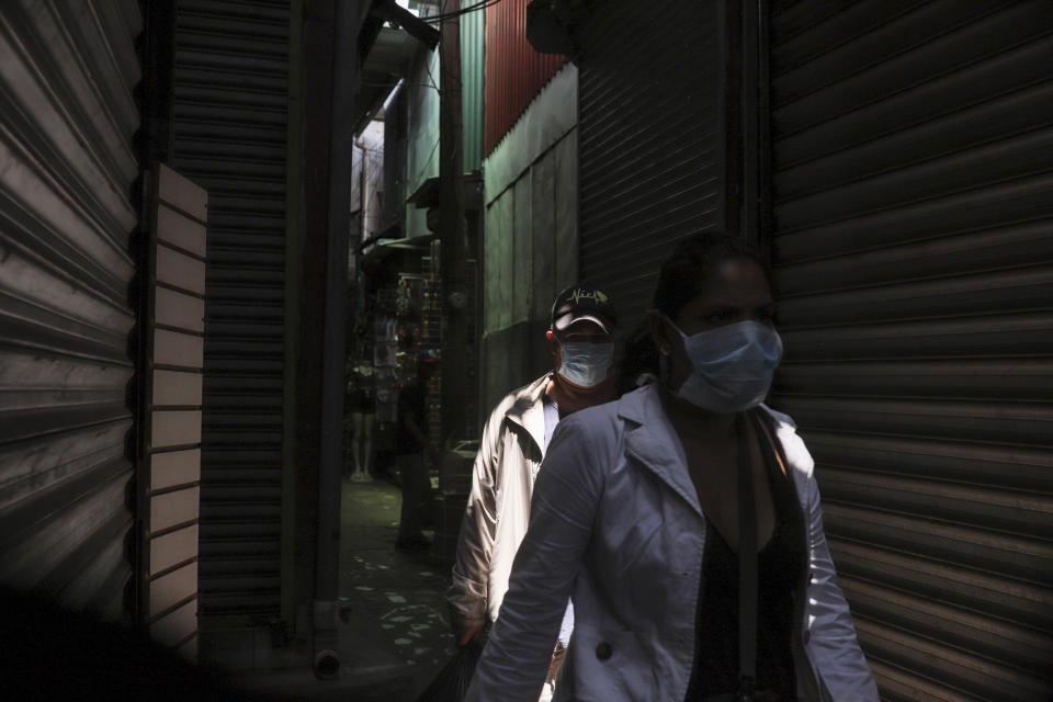 Dos personas, con las bocas cubierta por mascarillas, caminan por un mercado popular en Managua, Nicaragua, el 7 de abril de 2020. Los restaurantes están vacíos, hay poco tráfico en las calles y los bañistas escasean pese a ser Semana Santa aunque el gobierno pidió a los nicaragüenses que sigan con su vida pese a la pandemia de coronavirus. (AP Foto/Alfredo Zúñiga)