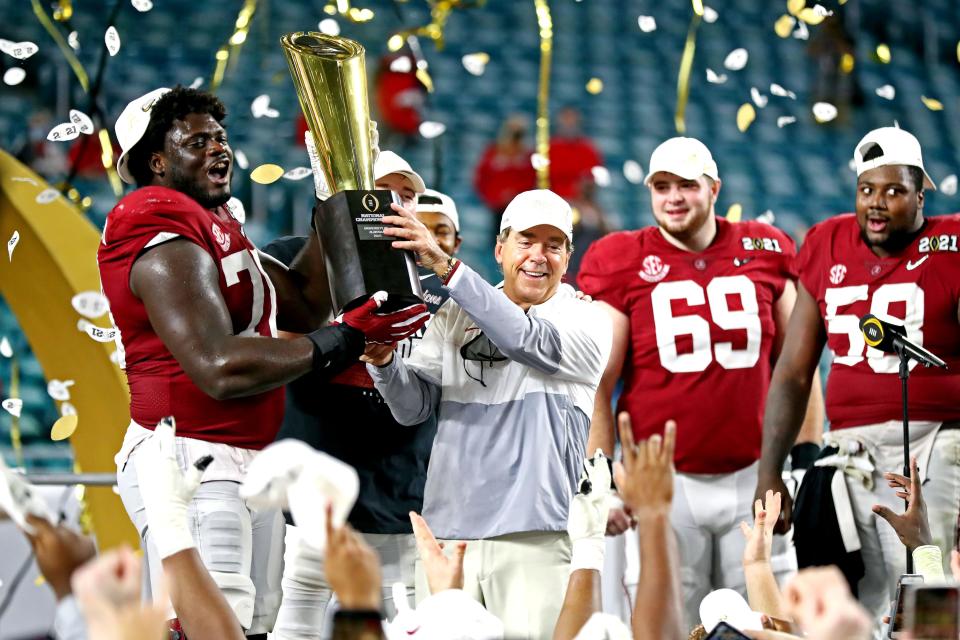 Alabama coach Nick Saban and offensive lineman Alex Leatherwood (70) celebrates with the College Football Playoff championship trophy after beating Ohio State to win the 2020 national title.