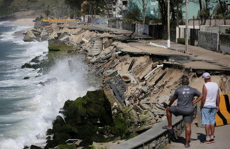 FILE PHOTO: Residents look at an exposed erosion along the boardwalk of Macumba beach after waves washed away the sand in the weekend storm, in Rio de Janeiro, Brazil October 17, 2017. REUTERS/Bruno Kelly/File Photo