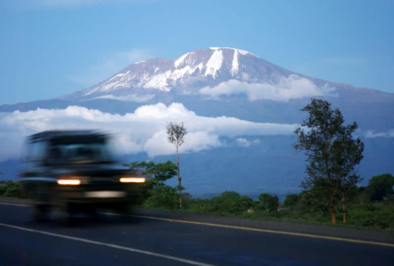 FILE PHOTO: A vehicle drives past Mount Kilimanjaro in Tanzania's Hie district