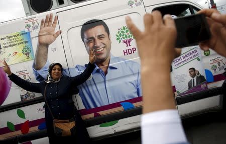 A supporter of pro-Kurdish People's Democratic Party (HDP) poses in front of an election campaign minibus with a picture of the party's co-chair Selahattin Demirtas on it, in Istanbul, Turkey, May 28, 2015. REUTERS/Murad Sezer