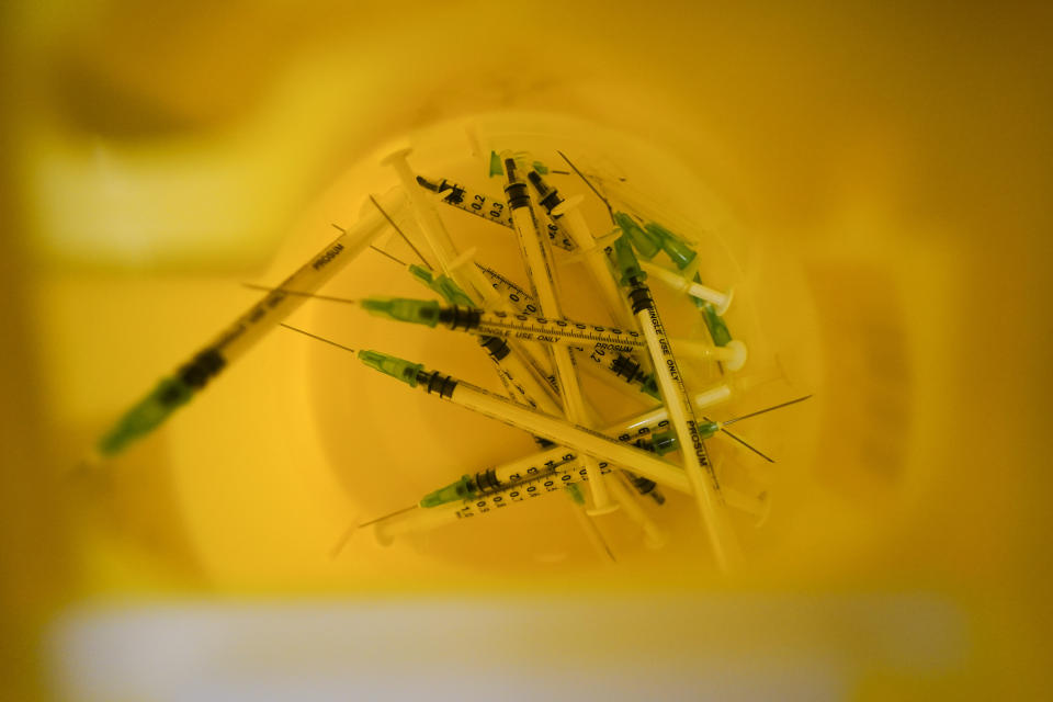 Used syringes in a bin at Swaminarayan School vaccination centre, in London, Saturday, Dec. 4, 2021. Britain says it will offer all adults a booster dose of vaccine within two months to bolster the nation's immunity as the new omicron variant of the coronavirus spreads. New measures to combat variant came into force in England on Tuesday, with face coverings again compulsory in shops and on public transport. (AP Photo/Alberto Pezzali)