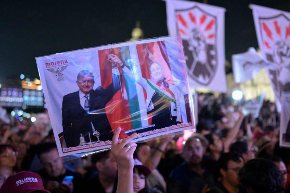 Una partidaria Claudia Sheinbaum y Andrés Manuel López Obrador con una fotografía de los dos en el Zócalo