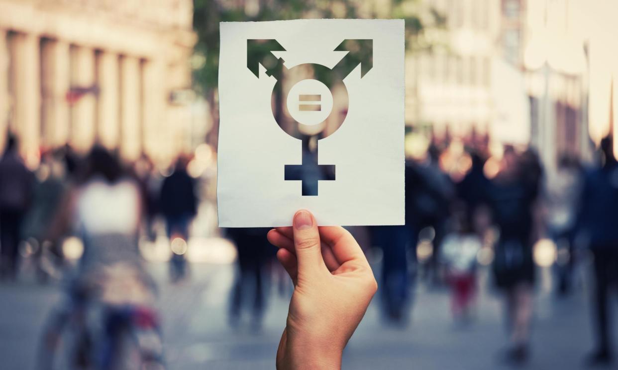 <span>Hand holding a paper sheet with transgender symbol and equal sign inside. Equality between genders concept over a crowded city street background. Sex</span><span>Photograph: Bulat Silvia/Alamy</span>