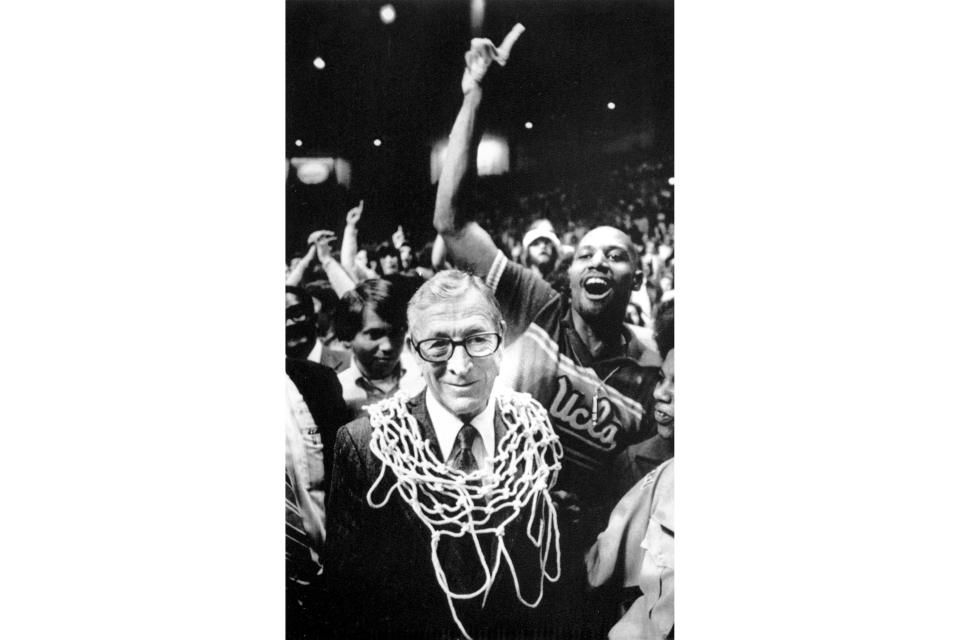 FILE - In this March 31, 1975, file photo, UCLA basketball coach John Wooden wears a basketball net around his neck after his team won the NCAA championship over Kentucky, 92-85, in San Diego. As Georgia begins its quest for an unprecedented three-peat in college football, those who have been there before can provide some helpful perspective on what it takes to keep winning titles year after year after year. (AP Photo/File)