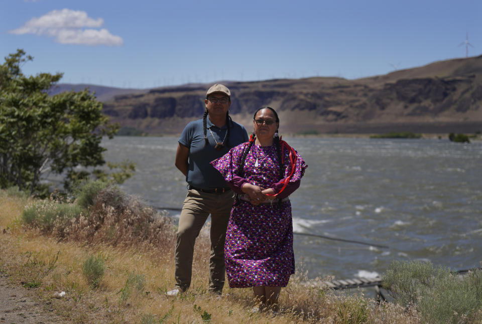 Bronsco Jim Jr., who was appointed mid-Columbia River chief, stands with his cousin Elaine Harvey, a fish biologist for Yakama Nation fisheries, at the banks of the Columbia River near the John Day Dam in Rufus, Ore., on Sunday, June 19, 2022. Harvey says the tribes are focused on preserving areas in tributaries such as the Klickitat and White Salmon, two glacial rivers that provide cold water for migrating salmon. (AP Photo/Jessie Wardarski)