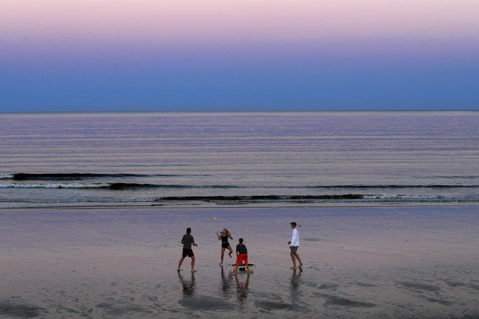 A group of people play Spikeball at twilight on the beach, Thursday, Aug. 7, 2020, in Ocean Park, Maine. As the summer tourist season reaches its peak Maine's coronavirus positivity rate remains among the lowest in the nation. (AP Photo/Robert F. Bukaty)