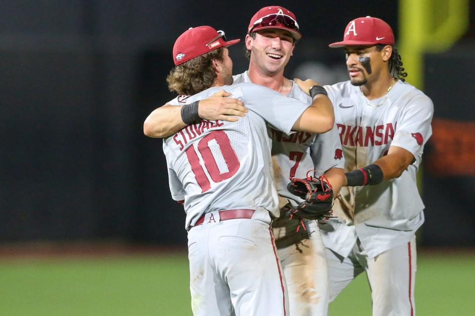 Arkansas infielder Peyton Stovall (10) hugs infielder Cayden Wallace (7) while infielder Jalen Battles (2) celebrates after beating Oklahoma St. 7-3 to win the Stillwater Regional at O'Brate Stadium in Stillwater, Okla. on Monday, June 6, 2022.(Ian Maule/Tulsa World via AP)