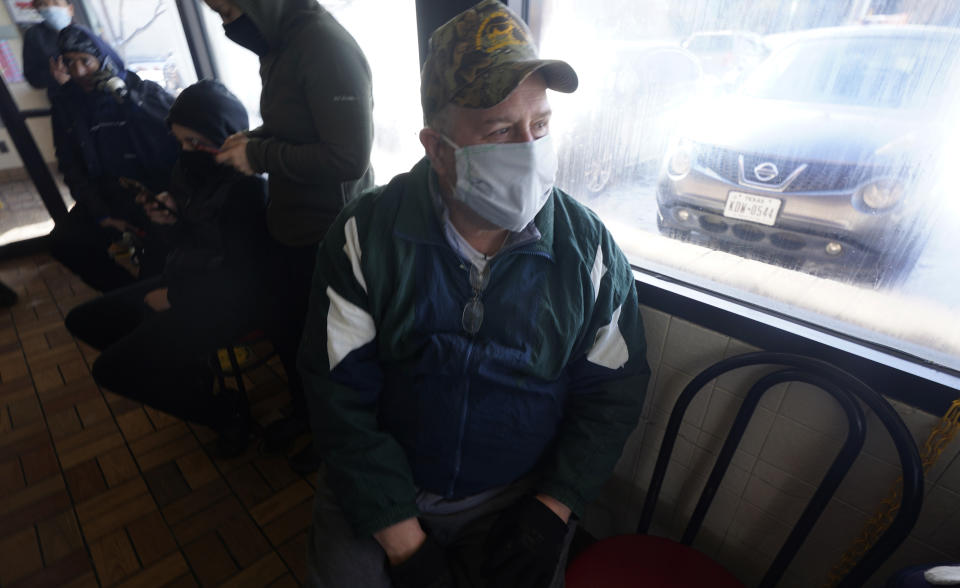 Because his house has been without power since last night, Donald Fuhrman sits in a warm but darkened restaurant Tuesday, Feb. 16, 2021, in Richardson, Texas. Temperatures dropped into the single digits as snow shut down air travel and grocery stores. (AP Photo/LM Otero)