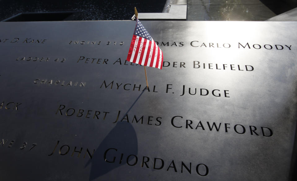 FILE - In this Monday, Sept. 12, 2011 file photo, a U.S. flag is stuck into the etched name of Father Mychal F. Judge, the New York Fire Department chaplain who died in the 9/11 attacks on the World Trade Center, at the National September 11 Memorial in New York. (AP Photo/Mike Segar, Pool, File)